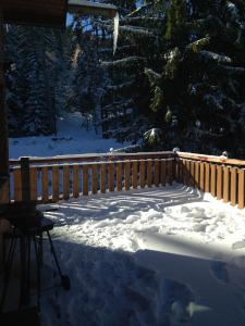 a snow covered porch with a fence and trees at chalet clémentine in La Tania