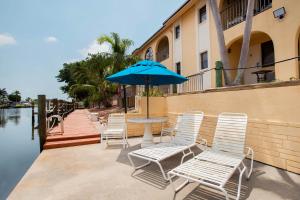 - une table avec des chaises et un parasol à côté de l'eau dans l'établissement OYO Waterfront Hotel- Cape Coral Fort Myers, FL, à Cape Coral