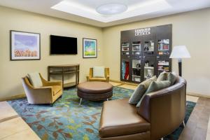 a waiting room with a couch and chairs and a tv at Candlewood Suites Virginia Beach Town Center, an IHG Hotel in Virginia Beach
