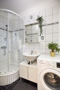 a white bathroom with a sink and a washing machine at Gemütliches Apartment in zentraler Lage in Graz