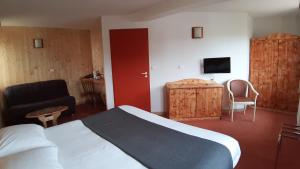 ジェラールメにあるHotel De La Route Verteのベッド、椅子、テレビが備わるホテルルームです。