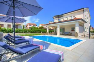 a villa with a swimming pool with chairs and an umbrella at Villa Magdalena in Porat