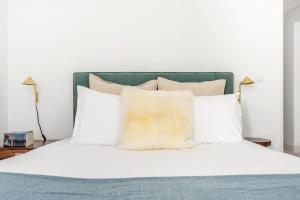 uma cama com almofadas brancas e uma cabeceira verde em Decompress at a Tranquil, Minimal Urban Oasis with an Edge no Porto
