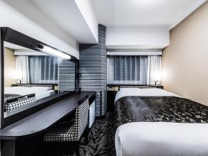 吹田市にあるアパホテル 〈新大阪 江坂駅前〉のベッド2台とデスクが備わるホテルルームです。