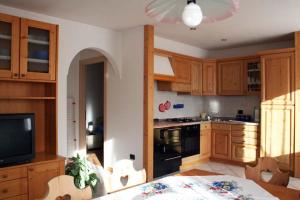 a kitchen with wooden cabinets and a table and a television at Appartamenti Piazzi in Tesero