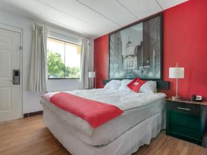 a bedroom with a large bed with a red wall at OYO Hotel Indianapolis International Airport in Indianapolis