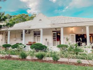 a white house with a garden in front of it at Ebony Lodge in Mthatha