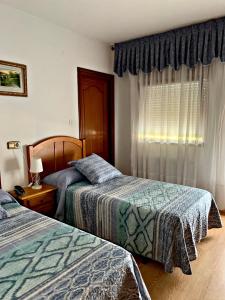 um quarto de hotel com duas camas e uma janela em Hostal Gabino em Isla