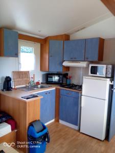 a kitchen with blue cabinets and a white refrigerator at Les chalets de Bes Le Montagnol in Lacombe