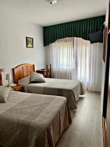 a hotel room with two beds and a window at Hostal Gabino in Isla