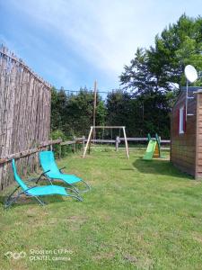 two chairs sitting in a yard with a playground at Les chalets de Bes Le Montagnol in Lacombe