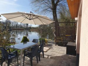 uma mesa e cadeiras com um guarda-sol em frente a um lago em Ferienoase an der Wublitz em Potsdam