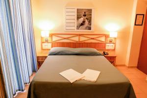 a bedroom with a bed with two papers on it at Hotel Villa Giulia in Porto Azzurro