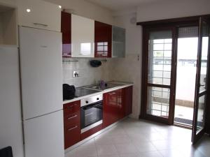 uma cozinha com armários vermelhos e um frigorífico branco em Graziosarisa Roma em Lunghezza