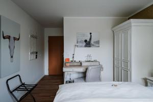 RobrookS Hotel Garni في Hiddenhausen: غرفة نوم بسرير ومكتب ومغسلة