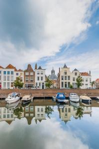 a group of boats docked in a river with buildings at Logement de Spaerpot in Middelburg