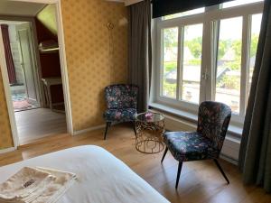 a bedroom with two chairs and a bed and a window at B&B Pastorie Jelsum in Jelsum