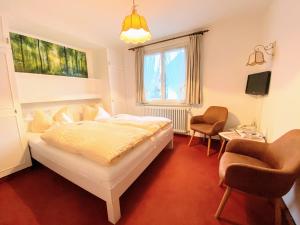ein Schlafzimmer mit einem Bett und zwei Stühlen darin in der Unterkunft Hotel Zartenbach B&B in Hinterzarten