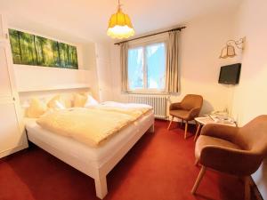 a bedroom with a bed and two chairs in it at Hotel Zartenbach B&B in Hinterzarten