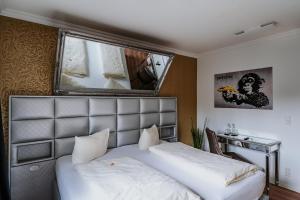 a bedroom with a bed and a desk and a mirror at RobrookS Hotel Garni in Hiddenhausen