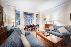una sala de estar con sofás azules y una mesa. en No1 The Mansions By Mansley, en Londres