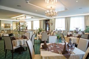 a dining room with tables and chairs and a chandelier at Hotel Jägerhof in Staatsbad Brückenau