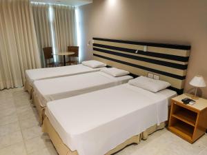 a hotel room with two beds and a table at Savassi Village in Belo Horizonte