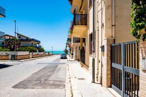 una calle vacía con edificios y el océano en el fondo en DELPOSTO Marina di Ragusa (lp), en Marina di Ragusa