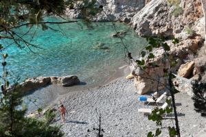 a person standing on a beach with rocks and water at Kalamitsi Hotel in Kardamyli