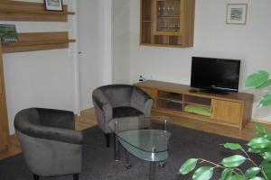 辛斯海姆的住宿－Am Mühlbach，客厅配有两把椅子和电视