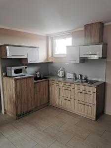 a kitchen with wooden cabinets and a microwave at Szabó Lux Apartman in Sárvár