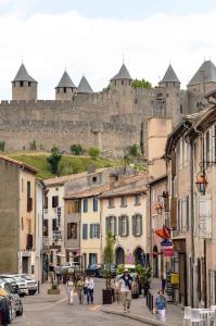 a group of people walking down a street with a castle at La Caponnière in Carcassonne