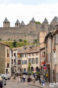 eine Gruppe von Menschen, die mit einem Schloss auf der Straße spazieren in der Unterkunft La Caponnière in Carcassonne