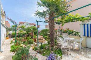 a garden with a table and chairs and a palm tree at Apartmani Križanović in Vodice