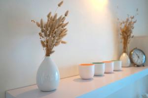 a row of white vases sitting on a shelf at Homey Experience - Terrace Sea View Apartment in Olbia
