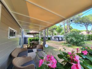a porch with chairs and an umbrella and flowers at Luxury Caravan at Union Lido in Cavallino-Treporti