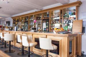 a bar with white bar stools in a room at The Clarendon Royal Hotel in Gravesend