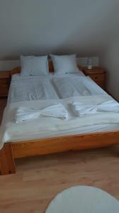 uma grande cama de madeira com lençóis brancos e almofadas em Rege apartman em Alsóörs