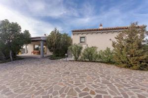 a house with a stone driveway in front of it at Villa Con Piscina Vista Mare in Cala Bitta