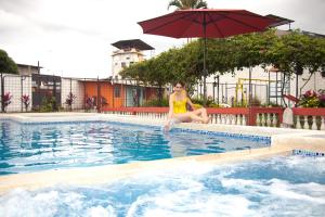 a woman sitting in a swimming pool with an umbrella at ZAFRA'S HOTEL in La Troncal