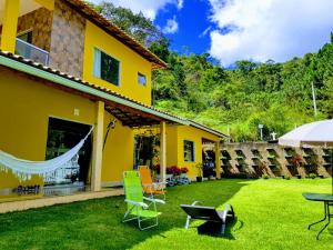 a house with a yard with chairs and a table at Casa Amarela, 03 suítes, pertinho do Valentim in Aracê