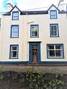 a white house with a blue door at Corsewall Arms Guest House in Stranraer