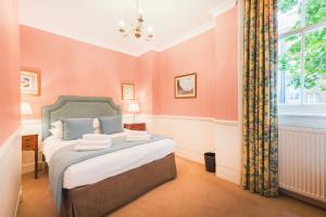 a bedroom with a bed with pink walls and a window at No1 The Mansions By Mansley in London