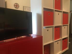a flat screen tv sitting on top of a red entertainment center at Buckingham Palace Apartman, Debrecen in Debrecen