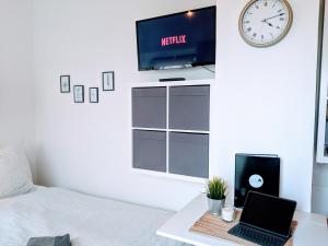 a bedroom with a bed and a laptop and a tv at Tiny Apartment - Innenstadt l Smart TV l Küche in Kaiserslautern