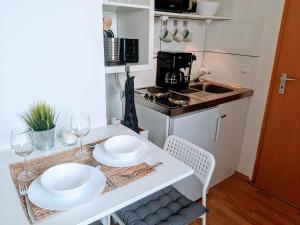 a small kitchen with a table with plates and wine glasses at Tiny Apartment - Innenstadt l Smart TV l Küche in Kaiserslautern
