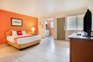 OYO Waterfront Hotel- Cape Coral Fort Myers, FL في كيب كورال: غرفة نوم بسرير وتلفزيون بشاشة مسطحة