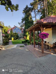 een paviljoen met tafels en stoelen en paarse bloemen bij Willa Pod Dębami in Świnoujście