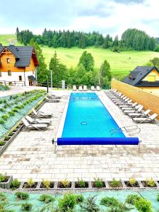 einen Blick über einen Pool mit Stühlen und ein Haus in der Unterkunft Lajkonik in Jaworki