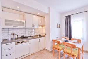 a kitchen with white cabinets and a table and chairs at Thomas Suites Datça in Datca